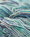 A close-up image of a multicolored worsted weight yarn skein with vibrant splashes of blue, teal, white, and green.