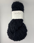 Black skein of boucle yarn with a label on a light gray background