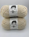 Two skeins of natural white yarn with labels on a gray background
