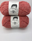 Two skeins of pink yarn with labels on a white background
