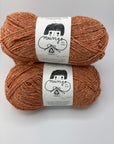 Two skeins of brown yarn with labels on a white background