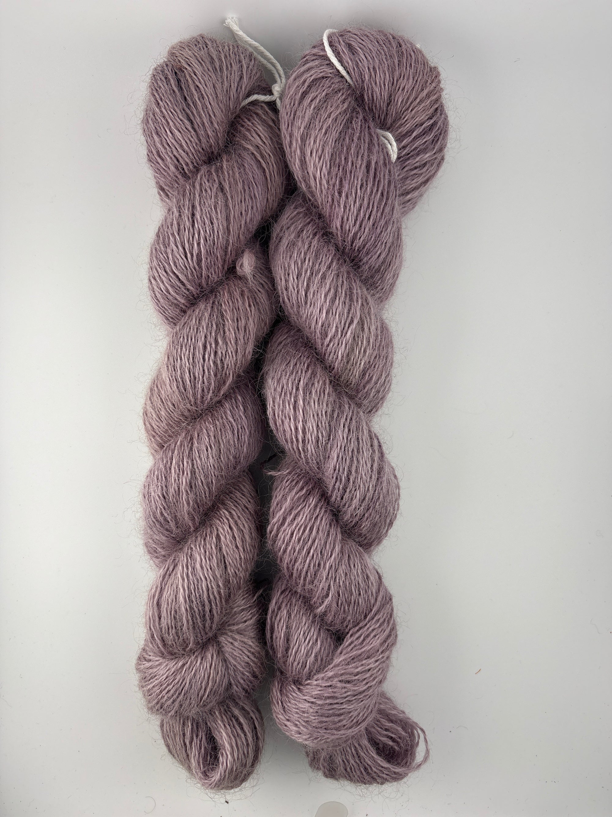Two skeins of purple yarn on a white background