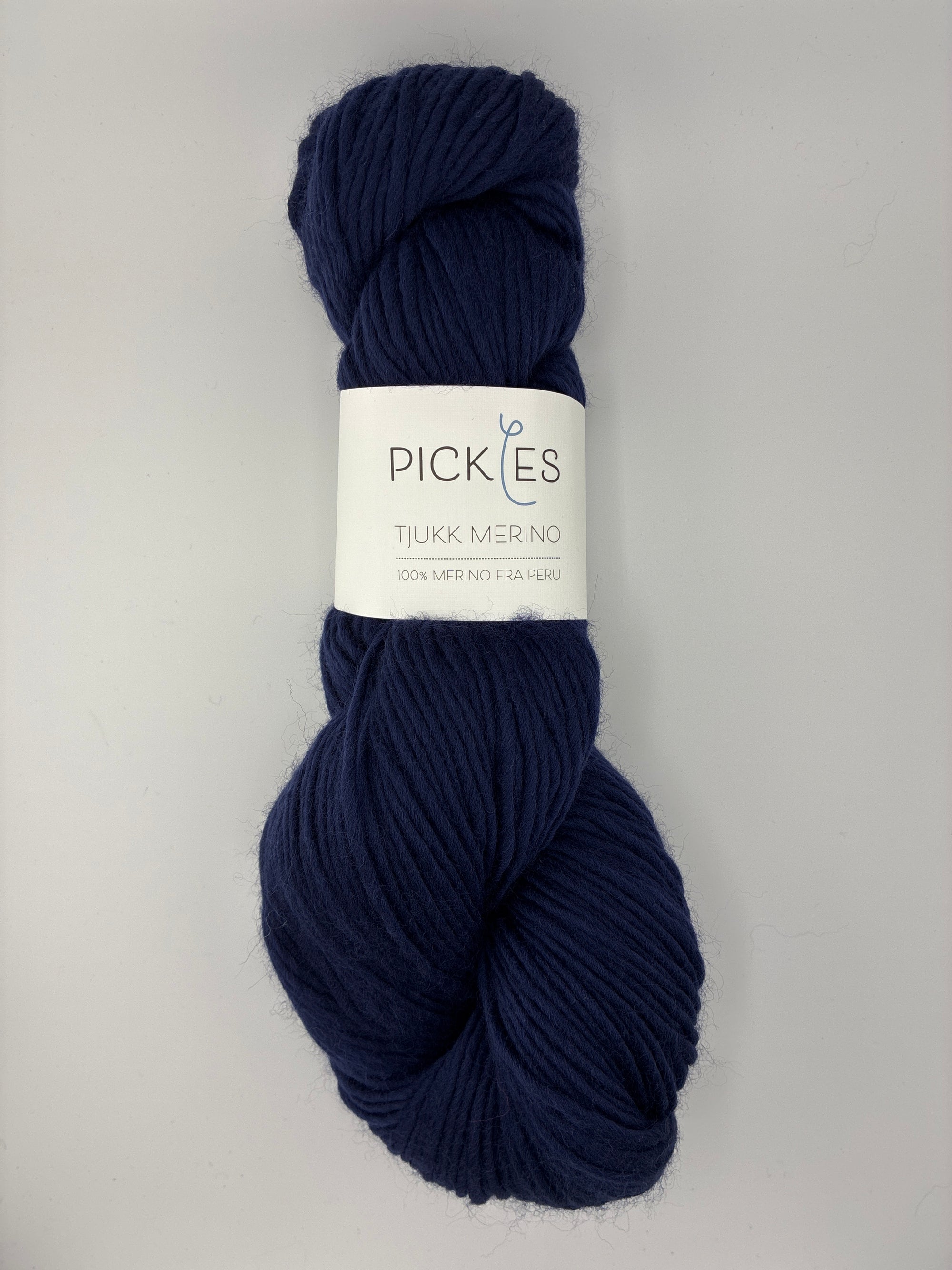 Navy blue skein of yarn with a label on a light gray background
