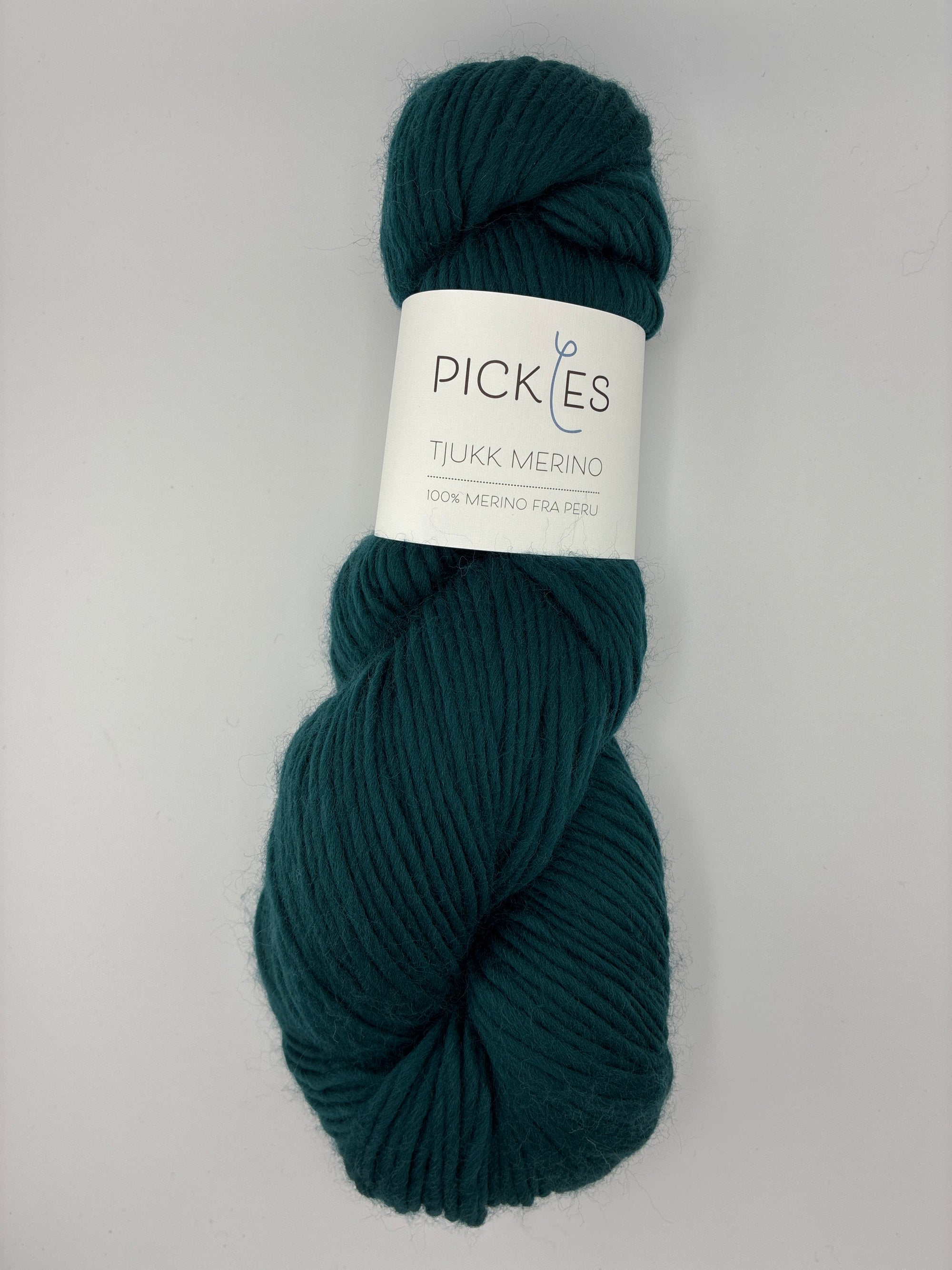 Dark Green skein of yarn with a label on a light gray background