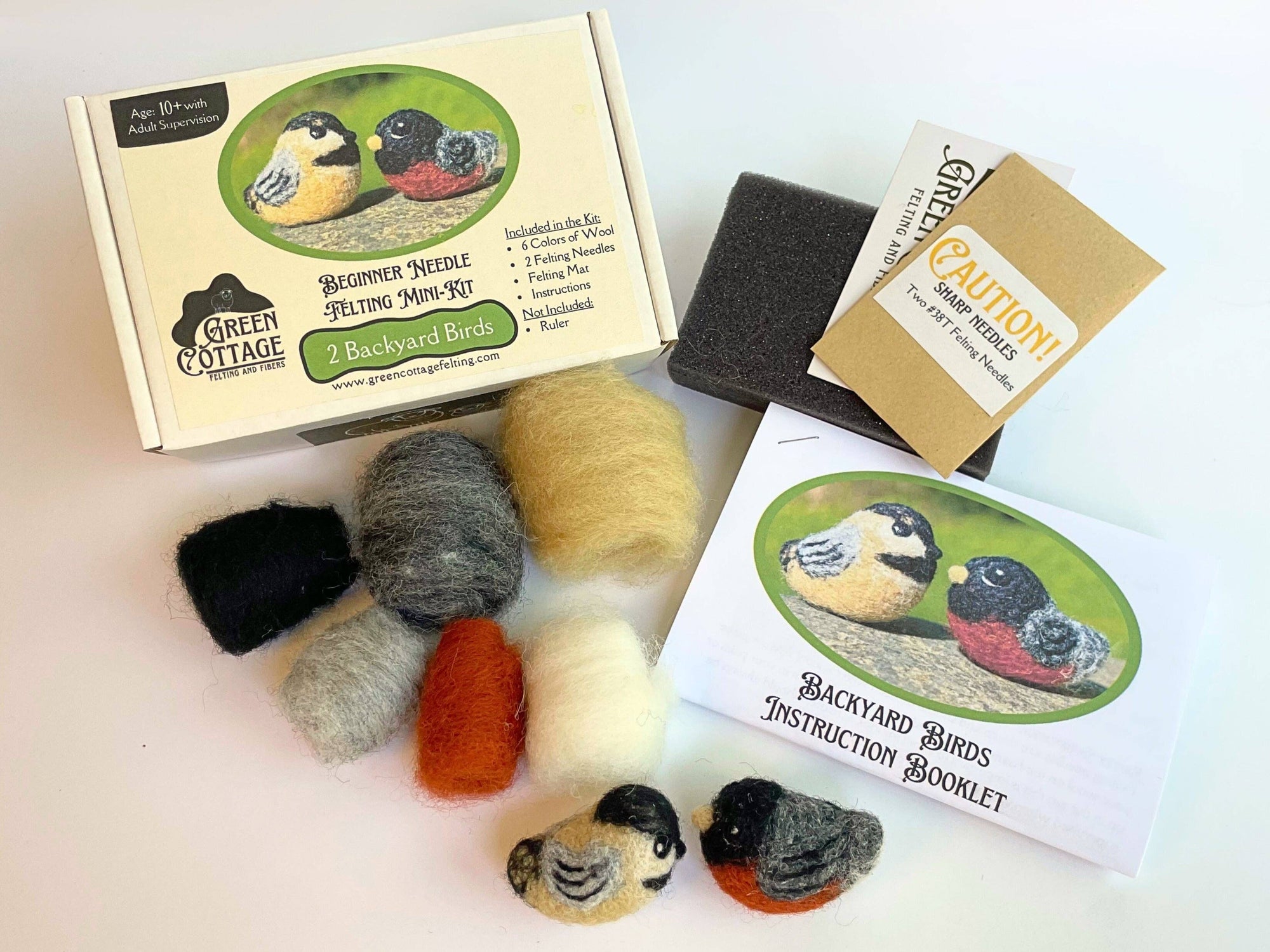 Green Cottage felting kit with yarn balls and bird figures on a white background
