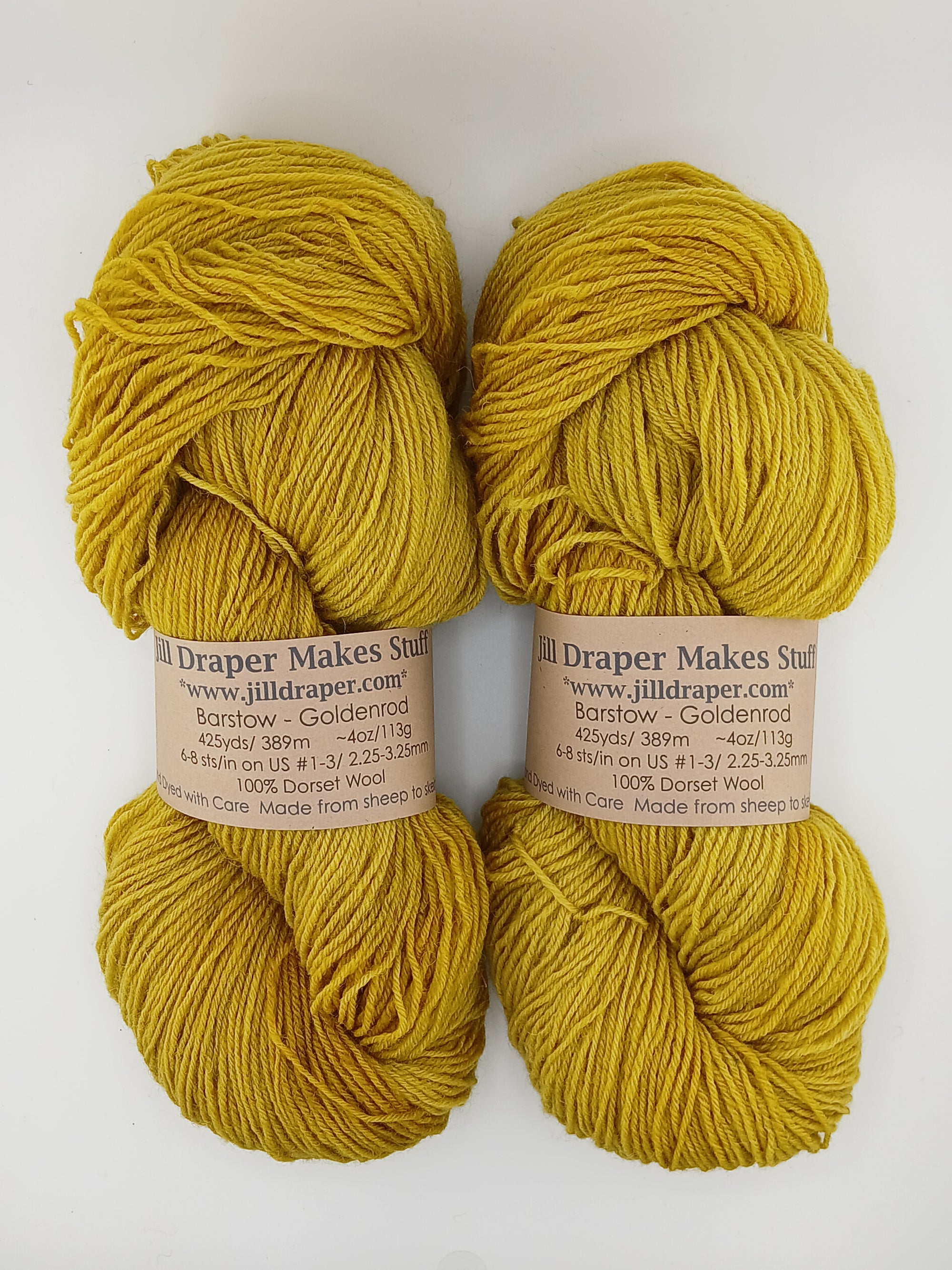 Two skeins of yellow yarn with labels on a white background