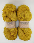 Two skeins of yellow yarn with labels on a white background