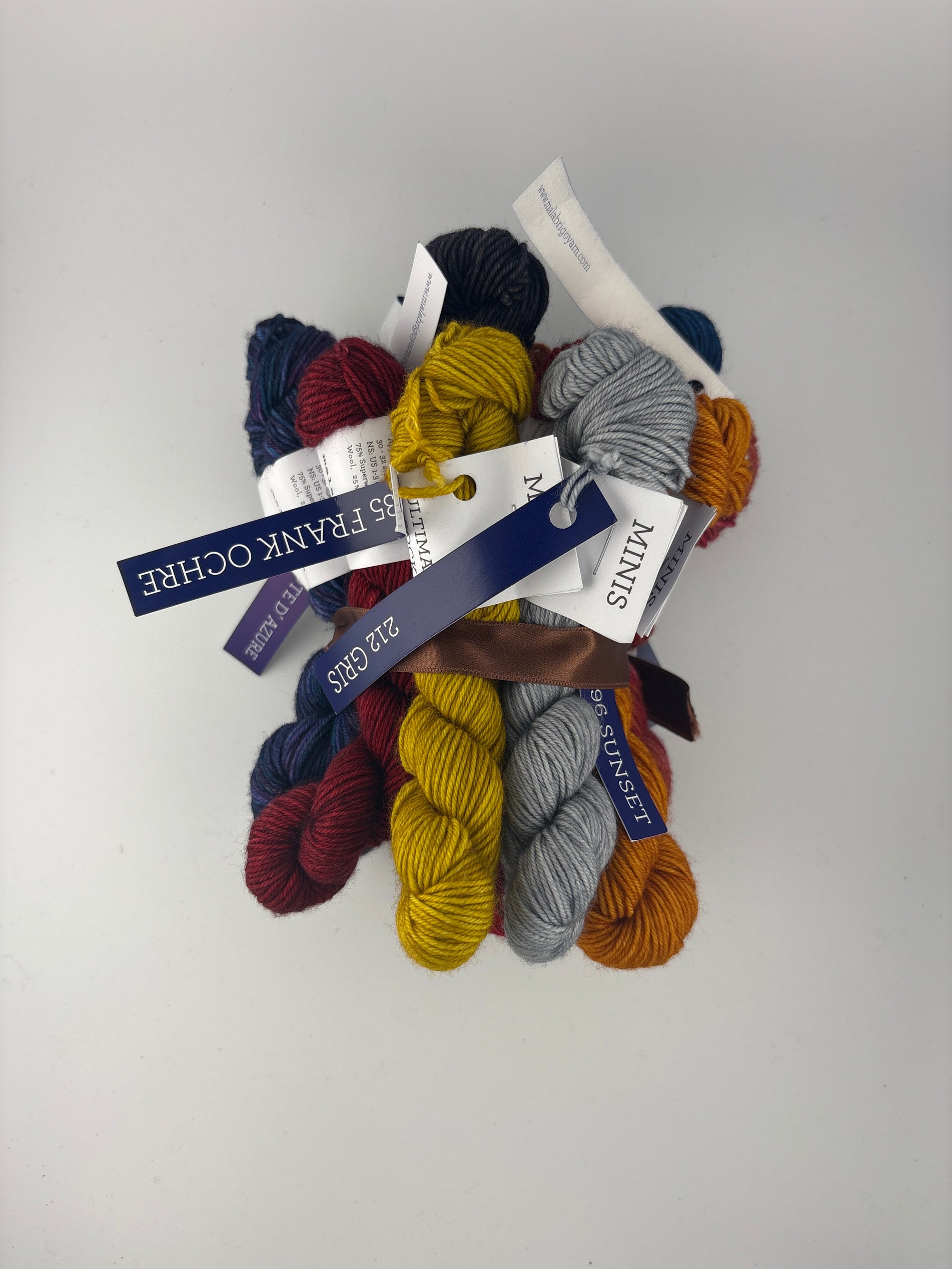 Collection of colorful Malabrigo Ultimate Sock yarn mini skeins with labels on a white background