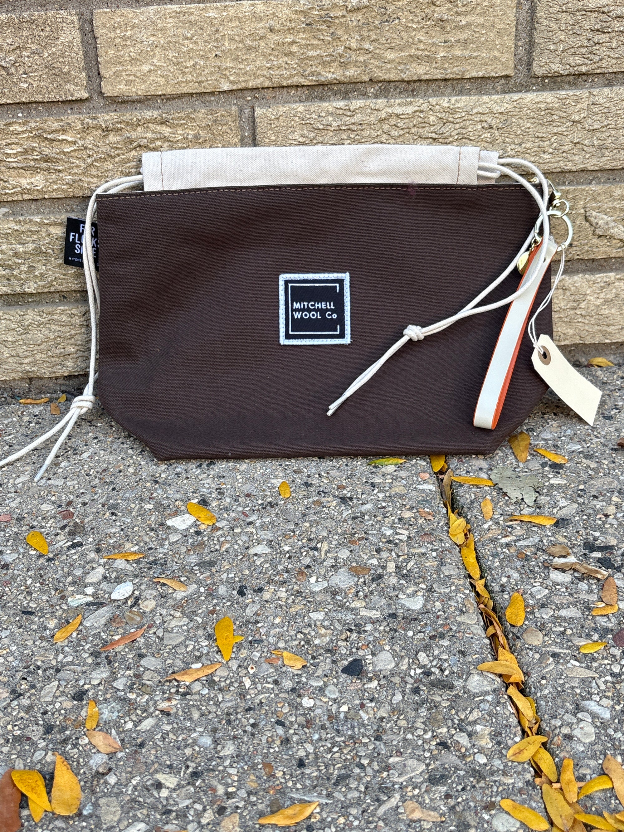 Brown bag with a Mitchell Wool logo on a stone and concrete surface
