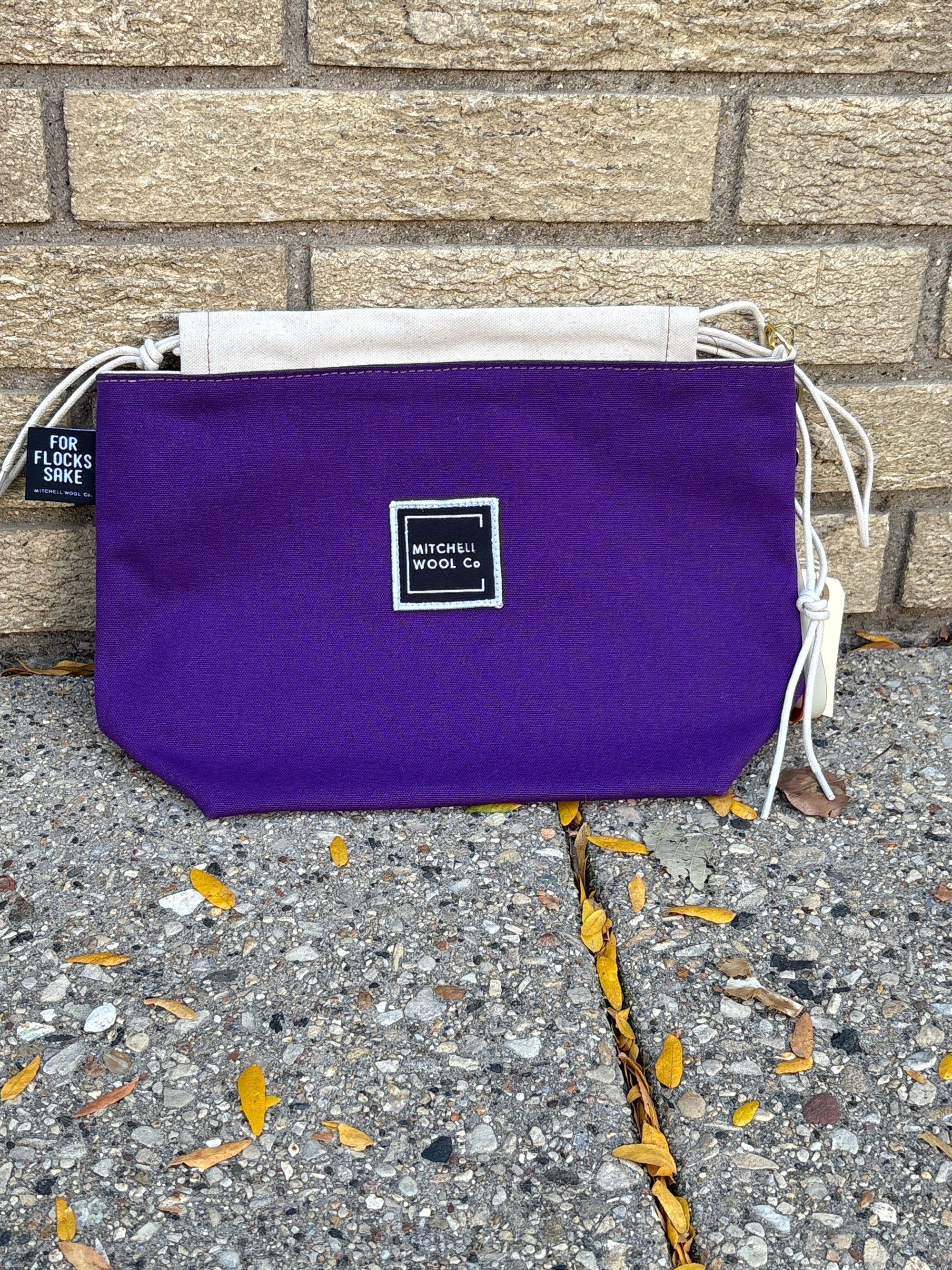 Mitchell Wool purple bag with a brand label on a pavement