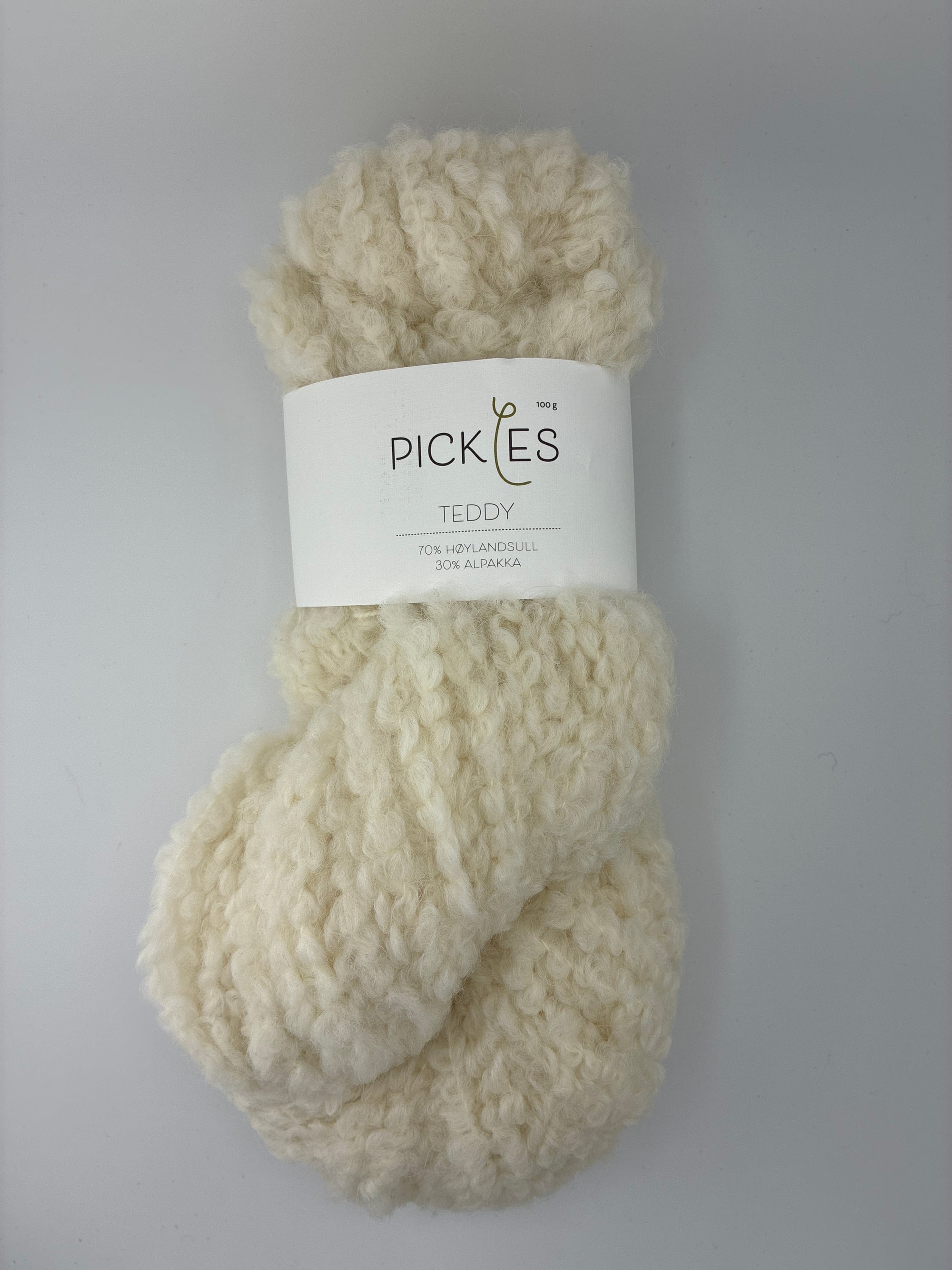 one skein of cream-colored boucle yarn with a label on a light gray background