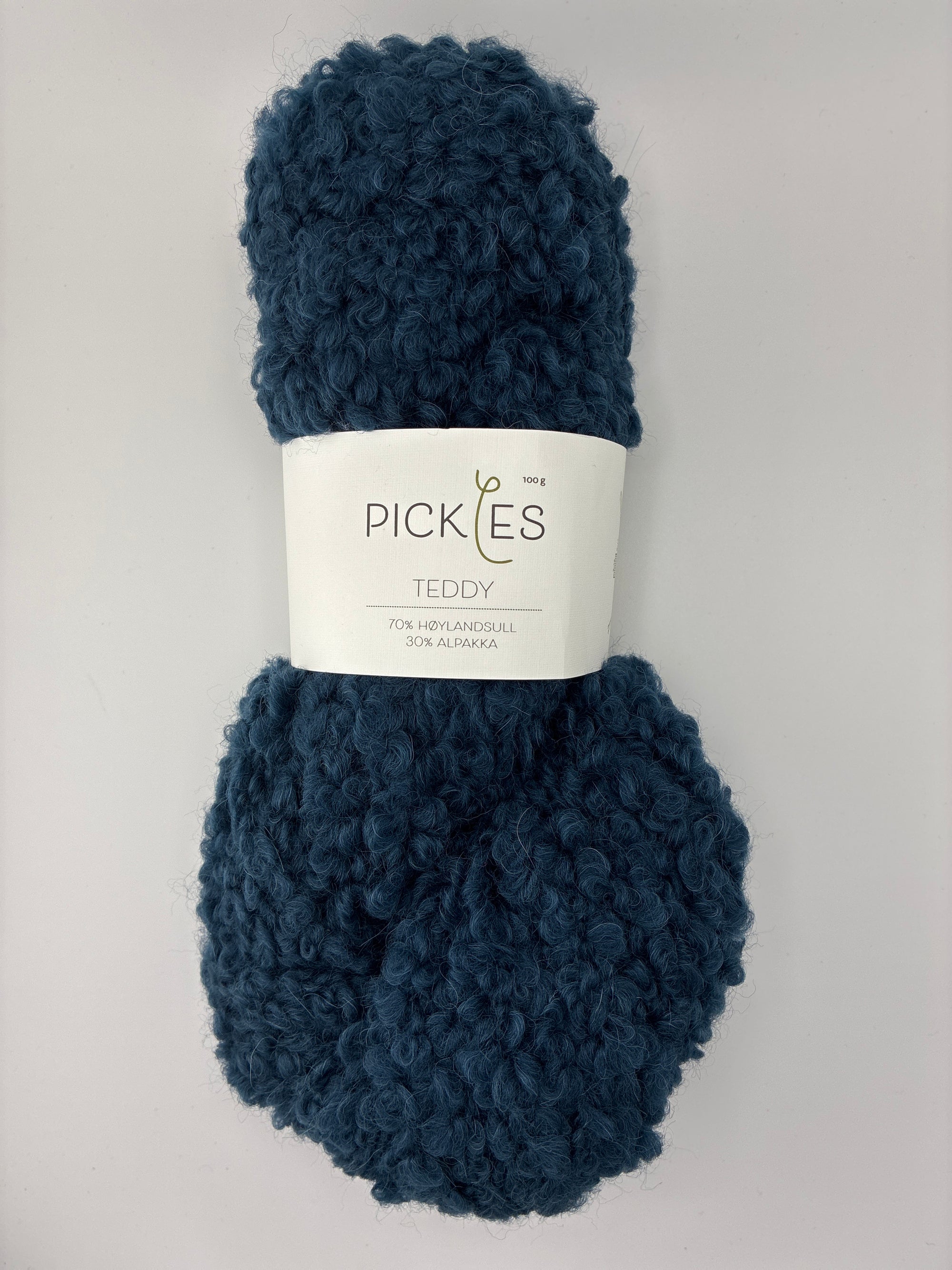 Ball of navy blue boucle yarn with a Pickles label on a light gray background