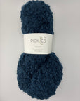 Ball of navy blue boucle yarn with a Pickles label on a light gray background