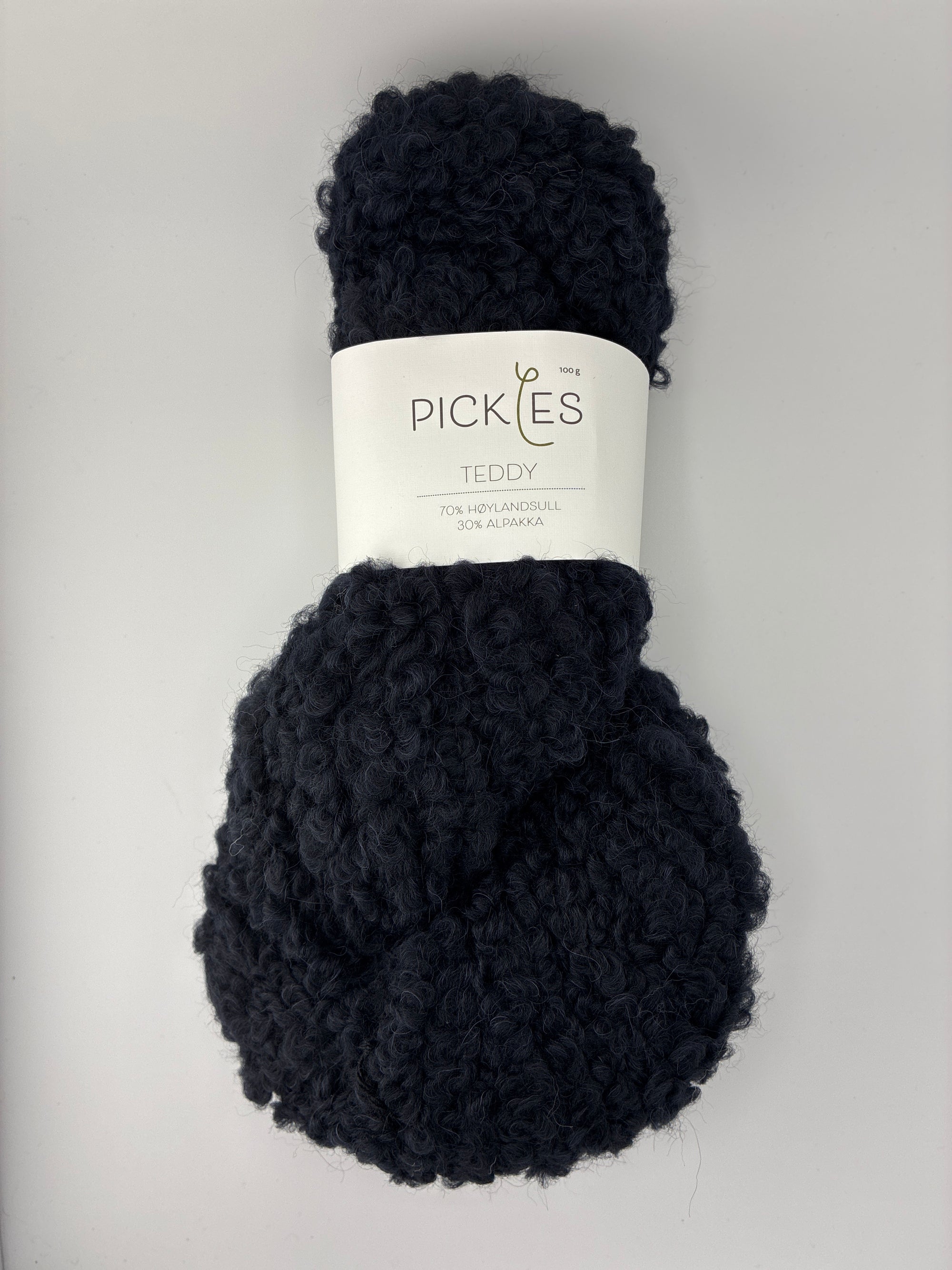 Black skein of boucle yarn with a label on a light gray background