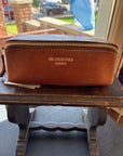 Brown leather knitting project bag with 'RE-DESIGNED PROJECT' branding on a wooden surface.