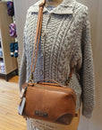 Mannequin wearing a textured sweater with a brown leather Re:Designed project bag.