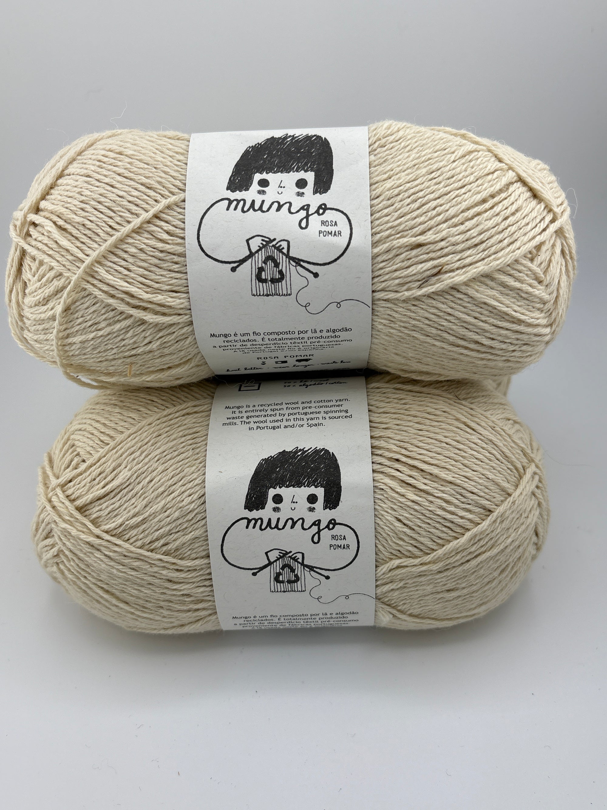 Two skeins of natural white yarn with labels on a gray background