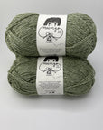 Two skeins of green yarn with labels on a white background