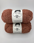 Two skeins of brown yarn with labels on a white background