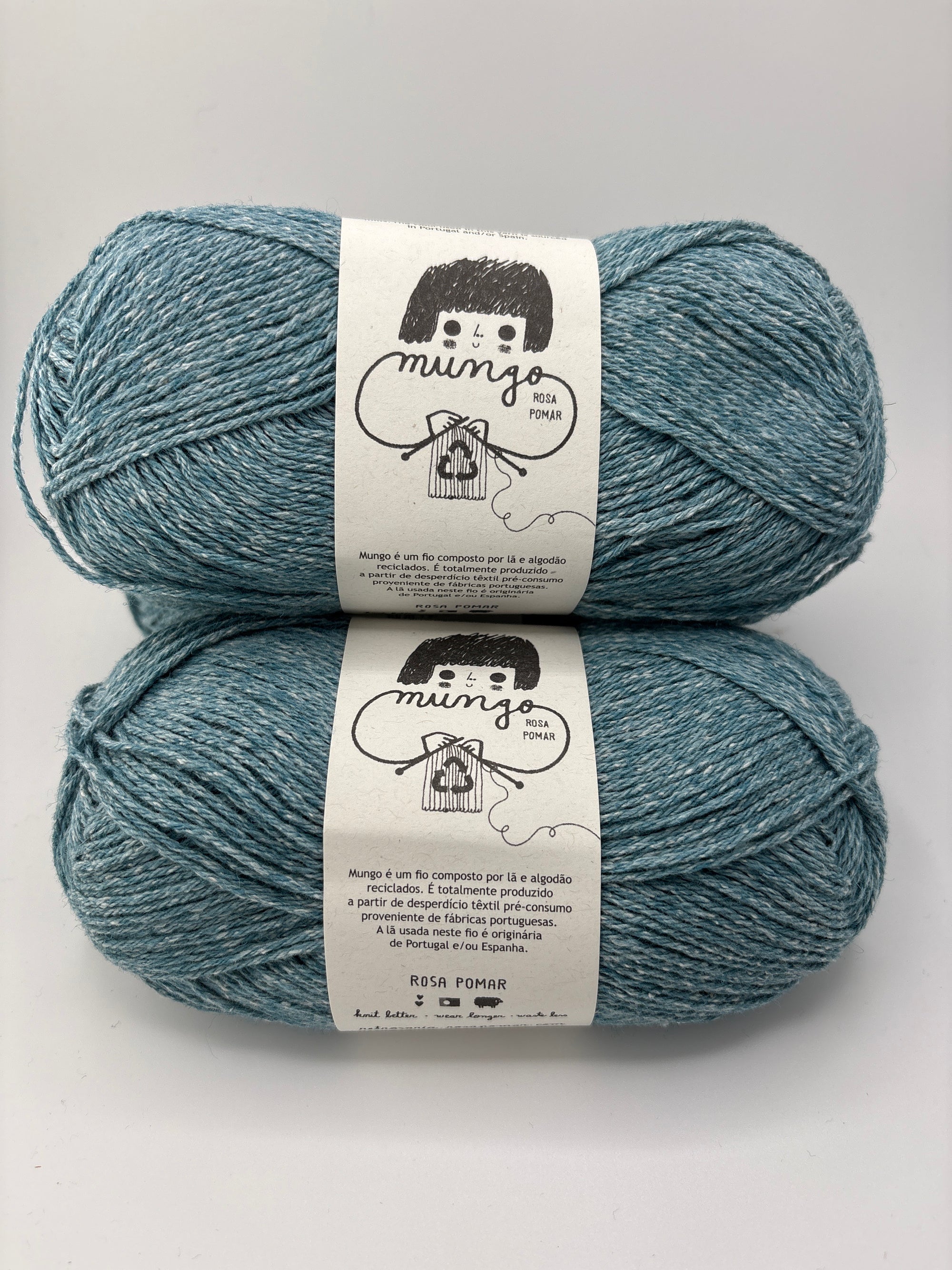 Two skeins of blue yarn with labels on a light gray background